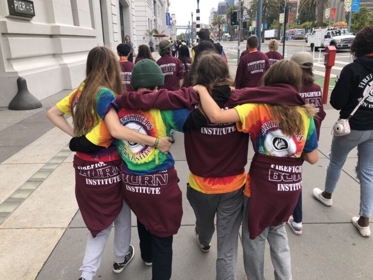 Students walking down street with arms around each other